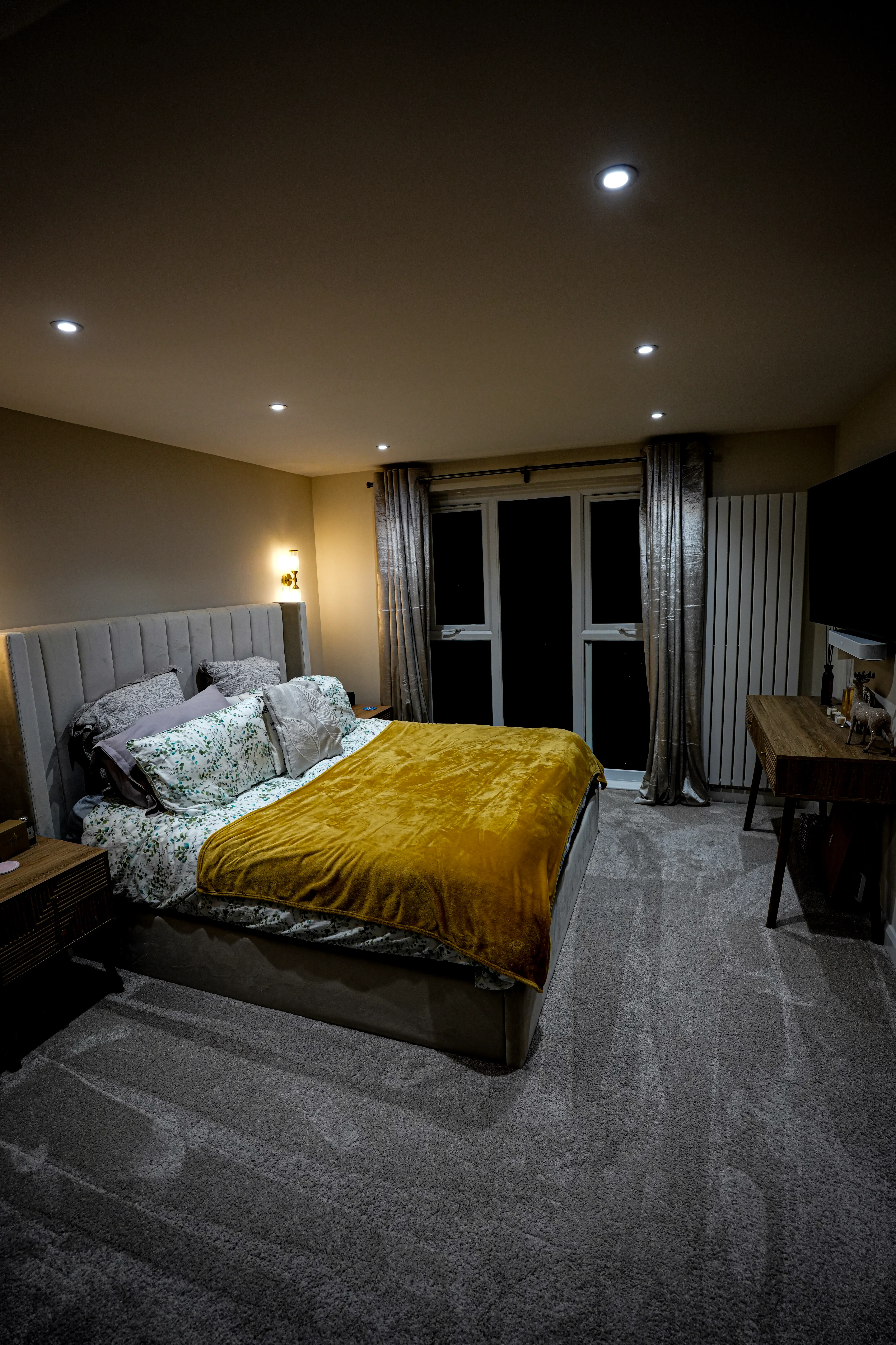 A bedroom with a large bed and a night stand.